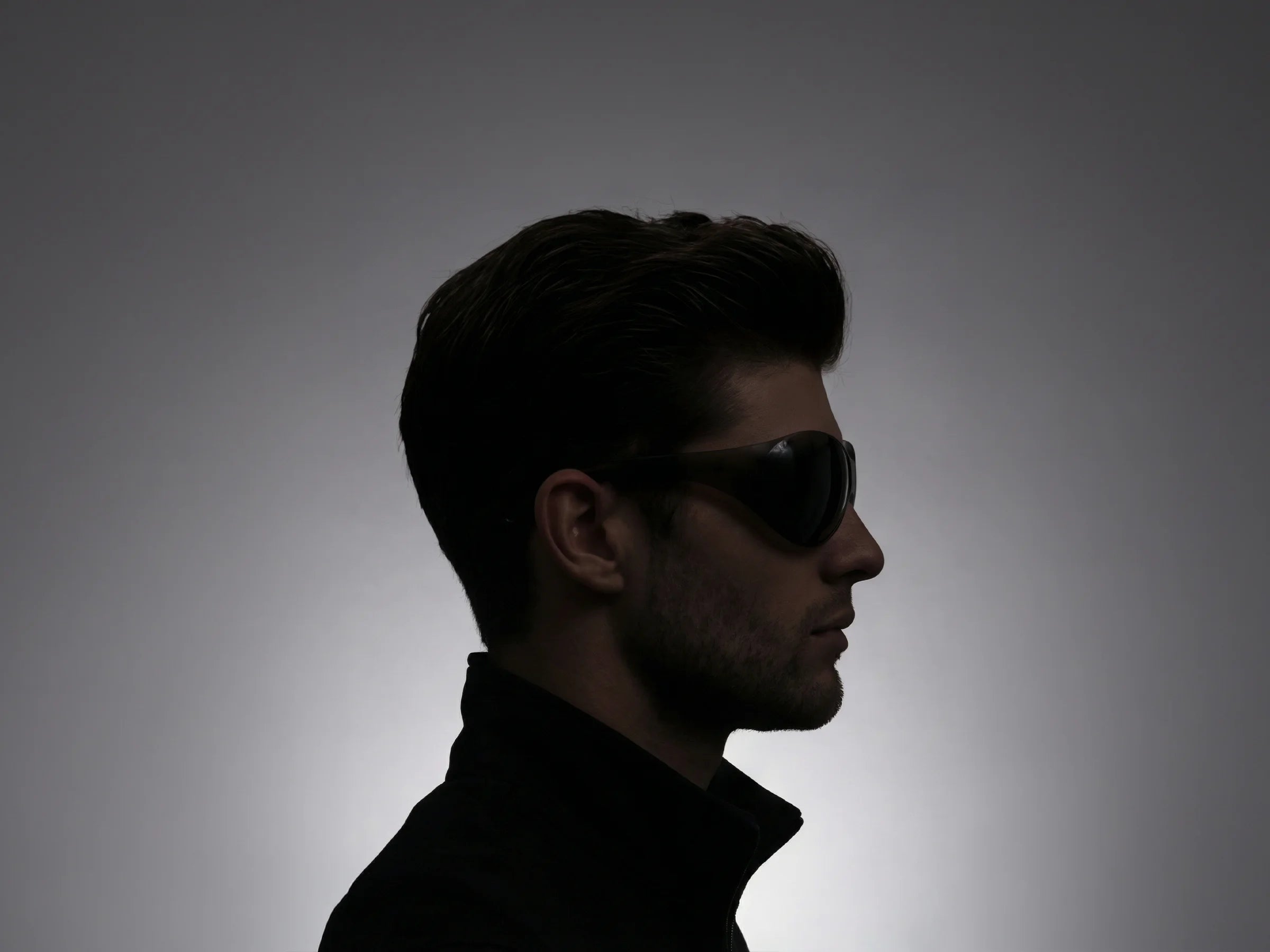 Silhouette of a person wearing sunglasses against a gray background