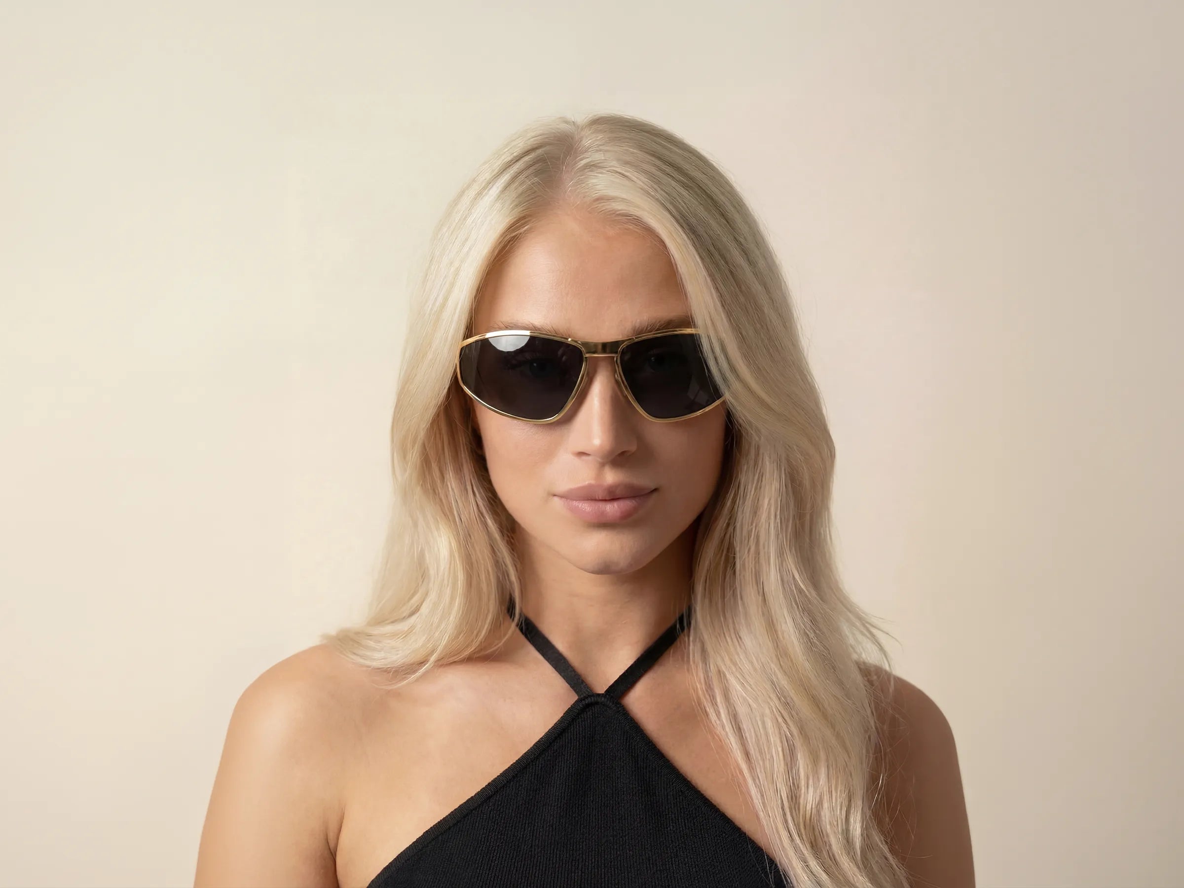 Woman wearing black theflyshades sunglasses and a black top against a beige background